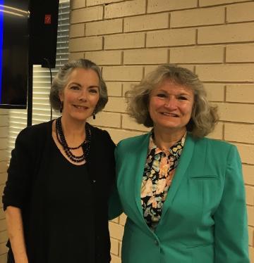 Two women smiling, one in black, the other in a green jacket.