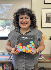 Alice Villatoro holding a physical copy of her e-book, SocialsVoice: Latino Youth Research on Social Media and Mental Health