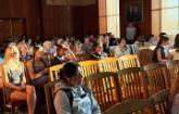 Students seated on wooden chairs in a wood paneled room listening to a presentation