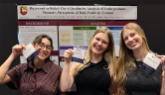 3 female students in front of their poster board at a conference