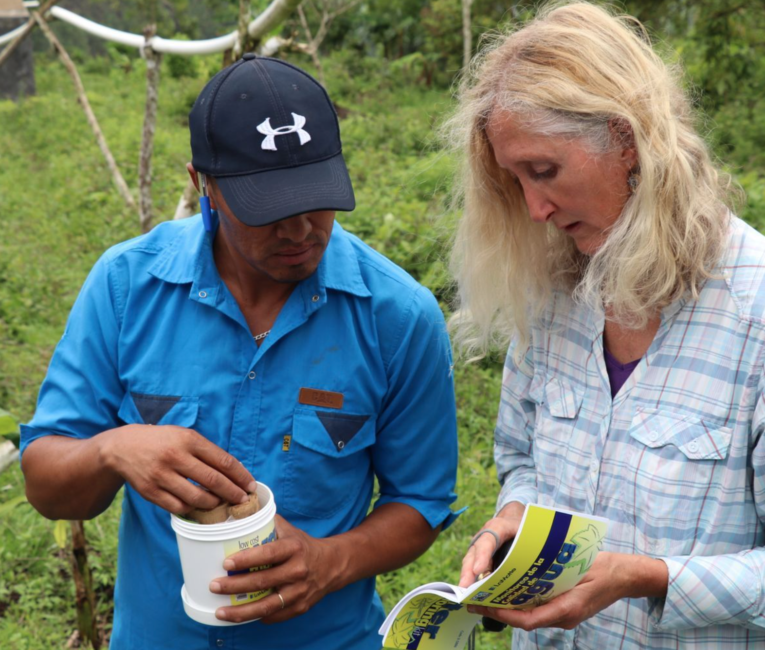 Two people examining a snake outdoors.