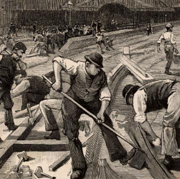 Workers engaged in labor-intensive construction in historical photograph.