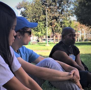 People sitting on grass, talking in a park.