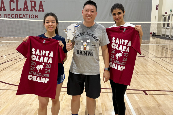 Picture shows three IM Badminton champs smiling in front of the courts with their tee shirts.