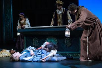 A theatrical scene from Romeo and Juliet with actors surrounding a coffin.
