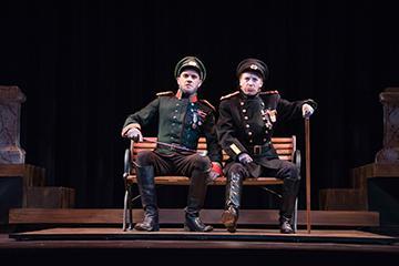 Two actors in formal attire sit on chairs on stage in The Good Doctor 4.