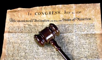 Gavel on a historical legal document titled We the People.