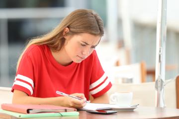 A person in a red shirt focused on studying at a table.