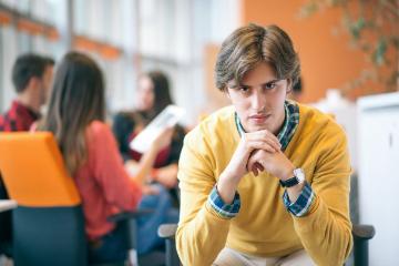 Person in yellow sweater appears focused, while others converse in the background.