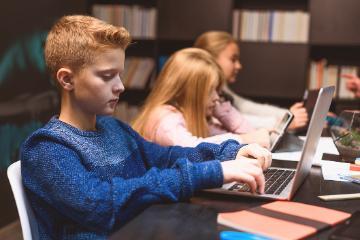 Students working on laptops in a classroom setting. 