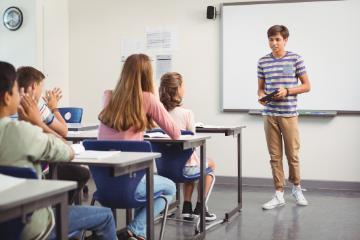Students listening to a teacher in a classroom presentation. 