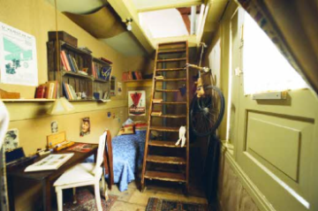 A re-creation of Anne Franks hiding place with a table, chair, and bookcase.