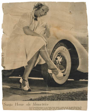 A woman sitting on a cars wheel.