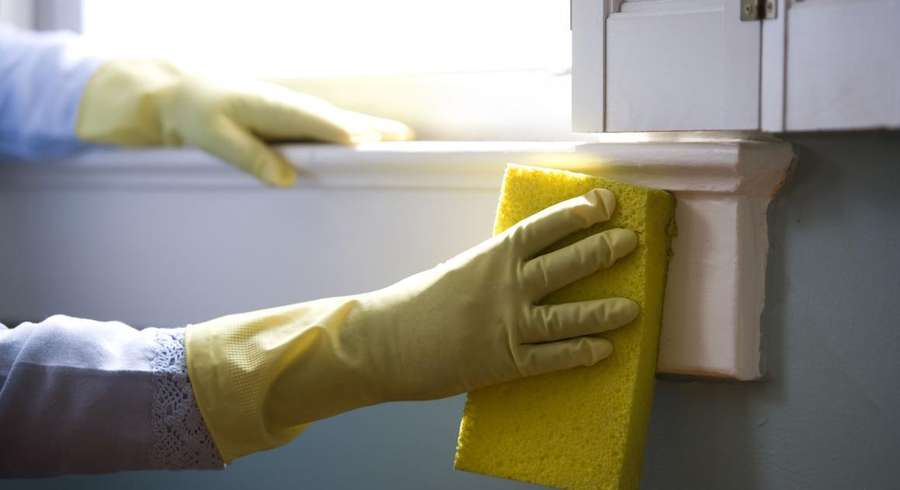Person wearing gloves cleaning a surface with a yellow cloth.