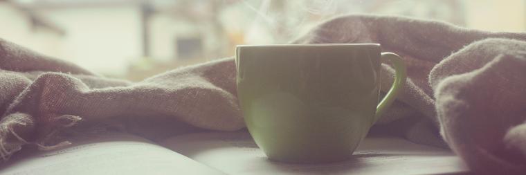 Two hands near a coffee mug on a table.