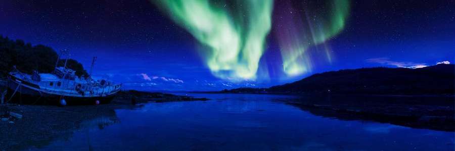 Alt text: Northern Lights illuminate a night sky over a lake.