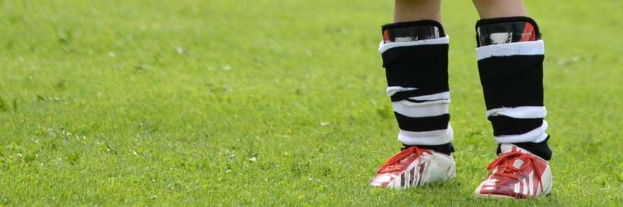 Football player wearing black socks standing on grass field.