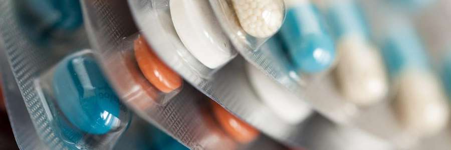 Blurred close-up of various multicolored pills in blister packs.