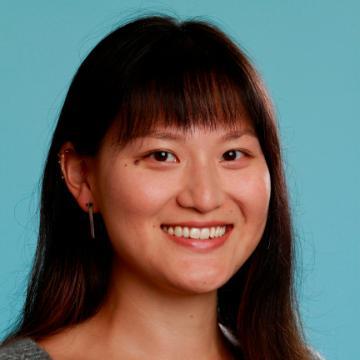 Smiling person in front of a plain blue background.