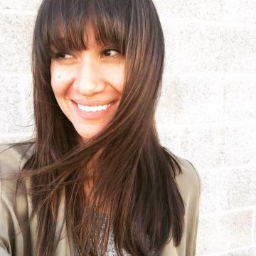 A woman smiling while looking away.