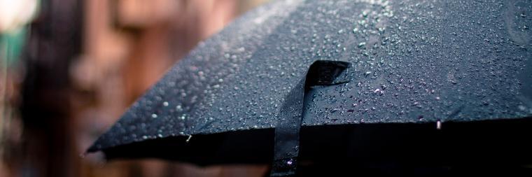 Open umbrella covered in rain drops