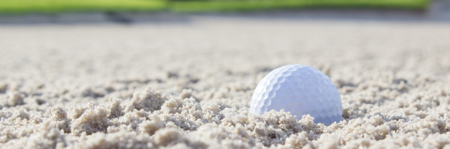 Photo of golf ball in sandtrap.