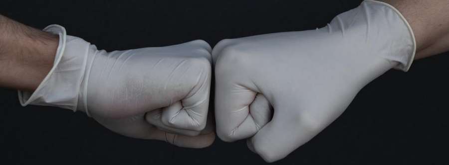 Photo of two fists in rubber gloves pushing eachother.